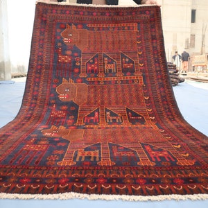 May include: A traditional hand-woven rug with a dark blue background and intricate patterns in shades of red, orange, and brown. The rug features a repeating design of stylized animals, possibly dogs or wolves, with geometric shapes and floral motifs.