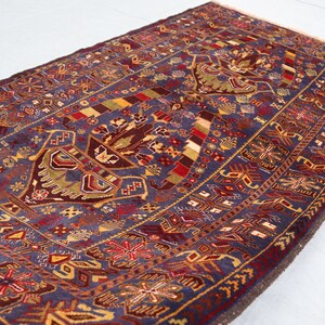 May include: A traditional Persian rug with a blue background and intricate patterns in shades of red, gold, and brown. The rug features a central medallion with floral motifs and geometric designs.