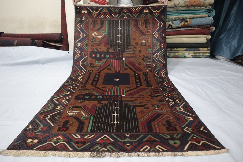 May include: A brown, black, green and red patterned rug with a geometric design. The rug has a fringed border.