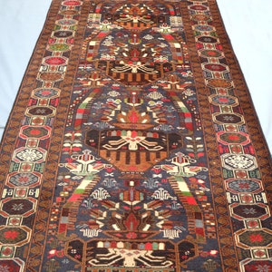 Può includere: Un tappeto lungo e stretto con uno sfondo blu scuro e motivi intricati in tonalità di rosso, marrone, bianco e verde. Il tappeto presenta un medaglione centrale con un disegno floreale e bordi geometrici.