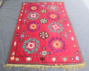 Può includere: Tessuto rosso con motivi floreali ricamati in bianco, giallo, verde e viola. Il tessuto ha un bordo con frange e un bordo grigio scuro. Il design presenta grandi fiori stilizzati e piccoli accenti floreali.