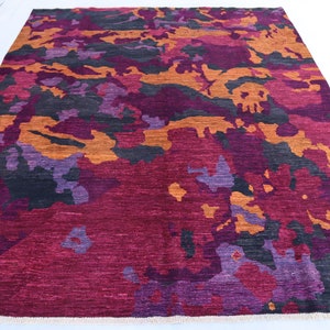 May include: Abstract area rug with a camouflage pattern in shades of purple, orange, and black.