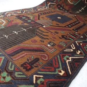 May include: A brown, blue, green and red patterned rug with a geometric design. The rug has a fringed border.