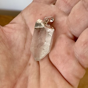 pendentif en quartz brut naturel dans la main

EN :
natural raw quartz pendant in hand