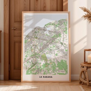 Puede incluir: Una impresión enmarcada del mapa de La Habana, Cuba, en un marco de madera clara. El mapa presenta un diseño detallado de las calles con áreas verdes que representan parques y espacios abiertos. El texto "LA HABANA" está impreso en la parte inferior.