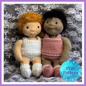 Puede incluir: Dos muñecas de punto con diferentes colores de pelo y tonos de piel están sentadas juntas. La muñeca de la izquierda tiene el pelo naranja rizado y lleva un conjunto de punto blanco. La muñeca de la derecha tiene el pelo negro y lleva un conjunto de punto rosa. Ambas muñecas llevan calcetines de punto.