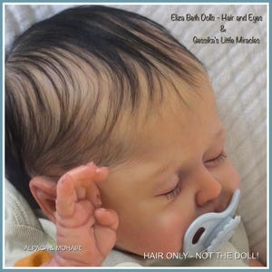 May include: A reborn doll head featuring rooted dark brown hair, closed eyes with long eyelashes, and a light blue pacifier. Text on the image reads: Eliza Beth Dolls - Hair and Eyes & Gessika's Little Miracles, ALPACA & MOHAIR, HAIR ONLY - NOT THE DOLL!