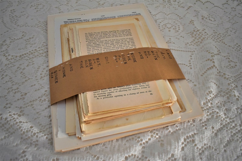 May include: A stack of vintage paper pages wrapped in brown paper with the text "AND THE MAN GOES AWAY" written on the paper.