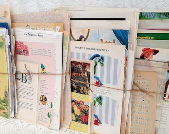 Op de afbeelding: Een stapel vintage papieren ephemera, waaronder pagina's uit een kinderboek, een muziekvel en een kaart. De papieren zijn met touw aan elkaar gebonden en hebben een rustieke, vintage uitstraling.