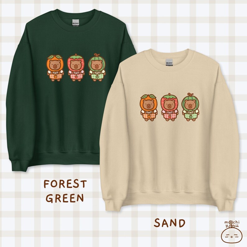 K&ouml;nnte beinhalten: Zwei Sweatshirts mit einem Design aus drei B&auml;ren, die Fruchtkost&uuml;me tragen. Das Sweatshirt links ist waldgr&uuml;n und das Sweatshirt rechts ist sandfarben.