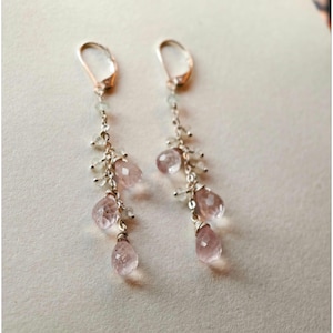 Peut inclure: Paire de boucles d'oreilles pendantes avec une chaîne argentée, de petites perles transparentes et des pierres précieuses roses en forme de goutte. Les boucles d'oreilles ont une fermeture à levier et sont présentées sur fond neutre.