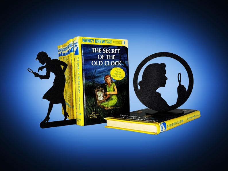May include: A display featuring vintage Nancy Drew mystery books, including "The Secret of the Old Clock." Black silhouette bookends depict a woman with a magnifying glass. The books have yellow spines and colorful covers.