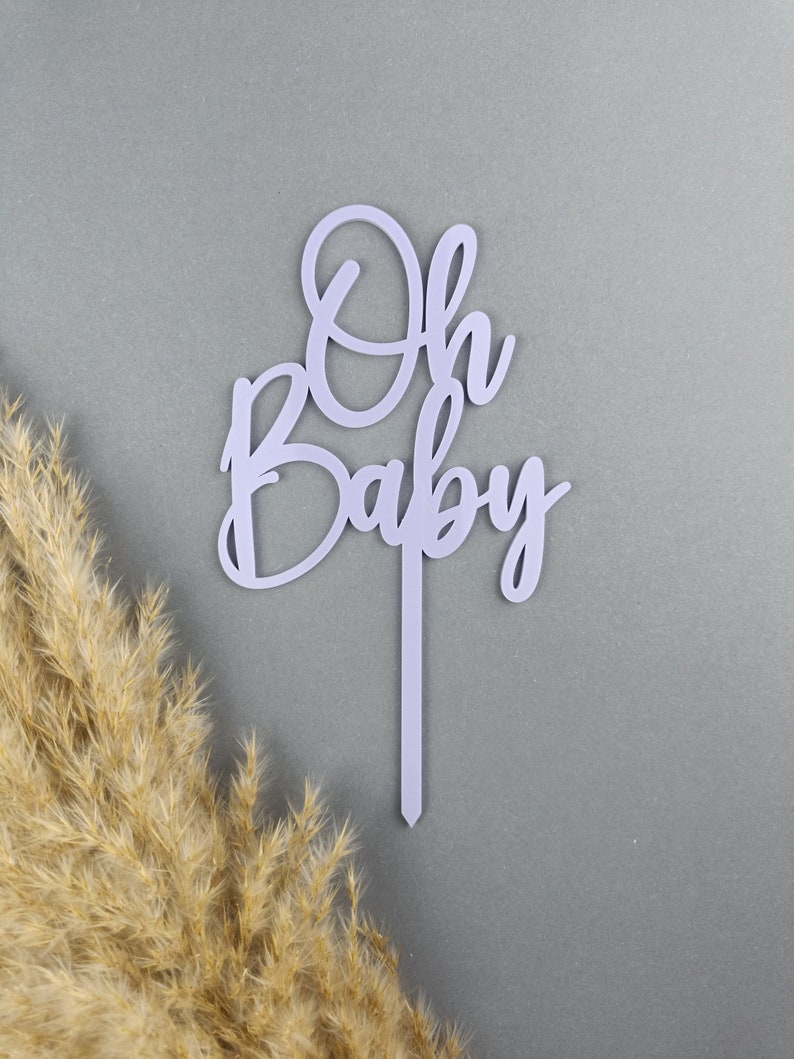 May include: Purple acrylic cake topper with the words "Oh Baby" in a cursive font.