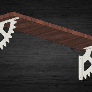 May include: Two white metal shelf brackets with a gear design. The brackets are attached to a wooden shelf.