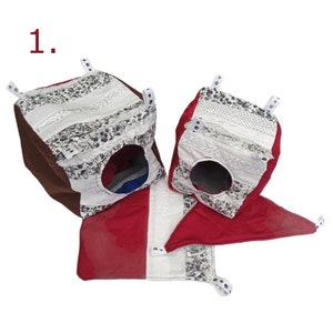 May include: Two brown and white patterned fabric pet houses with red fabric flaps. The houses are connected by a red fabric flap.