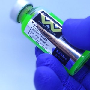 Könnte beinhalten: Eine kleine grüne Glasflasche mit einem weißen Verschluss und einem Etikett mit der Aufschrift "Yautja blood (Predator)". Das Etikett enthält auch den Text "Sample: 00825", "Specimen: Scarface", "Origin: Dark Blade Clan", "9335iu" und "25ml".