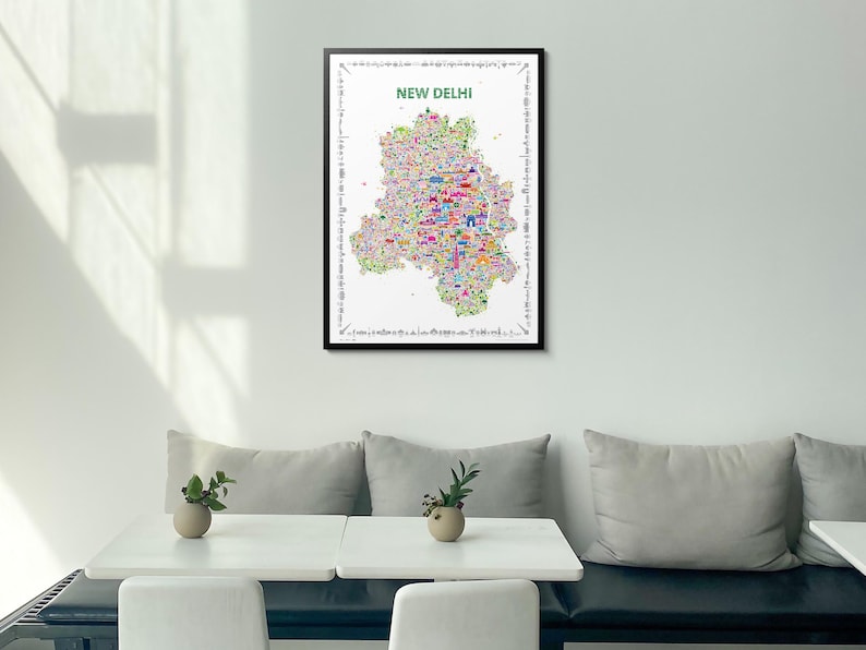 A framed wall art print featuring a colorful, detailed map poster of New Delhi. The map is filled with small, vibrant illustrations of landmarks and city elements, set against a white background with the text NEW DELHI at the top.