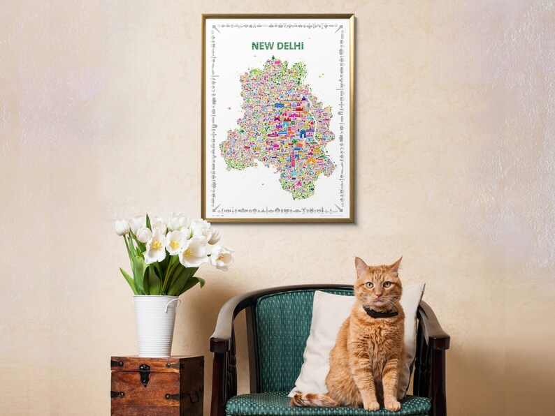 A framed wall art print featuring a colorful, detailed map poster of New Delhi, India. The map is set against a white background with the text NEW DELHI printed in green at the top, surrounded by a decorative border of small black icons.