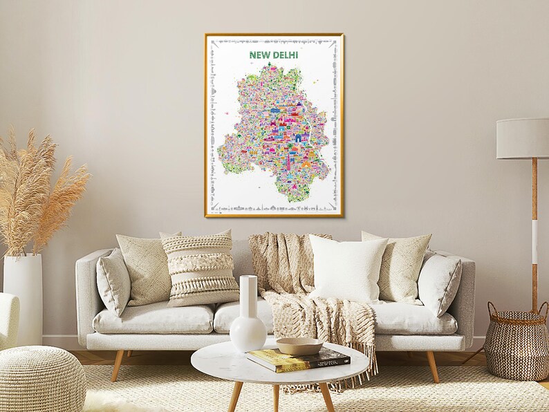 A rectangular wall art print featuring a colorful, detailed illustrated map of New Delhi. The map poster is set against a white background with the text NEW DELHI printed in green at the top, surrounded by a decorative border of small icons. It is a wall art travel souvenir artwork.