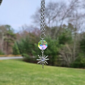 May include: A silver chain necklace with a iridescent crystal pendant and a silver snowflake charm.