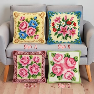 以下が含まれることがあります： グレーのソファに、花の模様が入った4つの正方形の装飾用クッションが展示されています。スタイルAは、黄色の背景にピンクと青のバラが特徴です。スタイルBはピンクのユリと赤い花があります。スタイルCはピンクのバラを示しています。スタイルDはピンクのバラがあります。