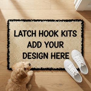 May include: A rectangular beige latch hook rug with black trim and the text "LATCH HOOK KITS ADD YOUR DESIGN HERE". White sneakers are placed on the right side of the rug. A small, light brown dog is lying on the left side of the rug.