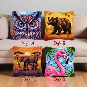 Op de afbeelding: Vier decoratieve sierkussens met dierenontwerpen. Stijl A toont een gedetailleerde uil, stijl B een beer, stijl C olifanten bij zonsondergang en stijl D een flamingo. Elk kussen heeft een getextureerde, gefranjerde rand en de stijl is aangegeven.