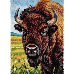May include: A detailed rug depicting a bison's head, with a focus on its face and horns. The bison has brown fur, dark eyes, and curved horns. The background shows a field of yellow and green grass under a blue sky.
