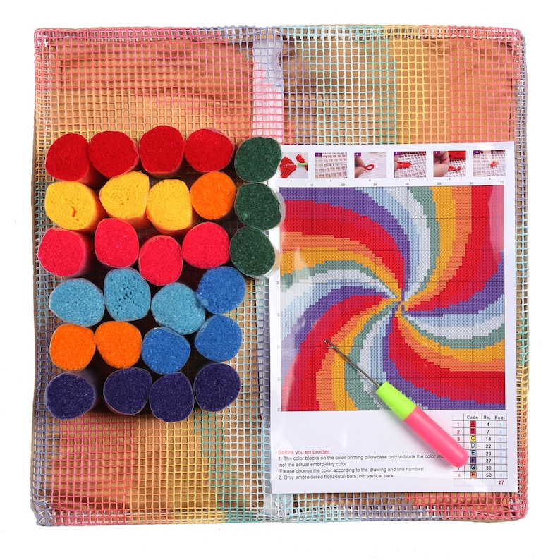 May include: A colorful latch hook kit with a rainbow swirl design. The kit includes a canvas, yarn in various colors, a hook, and a pattern guide. The yarn colors include red, yellow, green, blue, and orange.