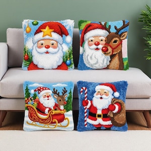 May include: Four square Christmas cushions with Santa Claus designs. Each cushion features a different Santa illustration, including one with a reindeer, one with a sleigh, and one holding a candy cane. The cushions have a blue background.