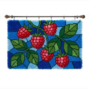 May include: A rectangular latch hook wall hanging featuring a stained glass style design of red raspberries and green leaves against a blue background. The textile piece is suspended from a dark metal rod with decorative finials and metal rings.