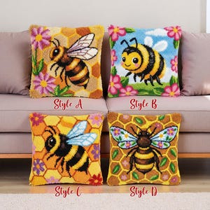 May include: Four decorative throw pillows with bee designs. Style A features a bee on a honeycomb background with pink flowers. Style B shows a cartoon bee with a blue sky and flowers. Style C has a bee with blue wings. Style D has a bee with floral wings.