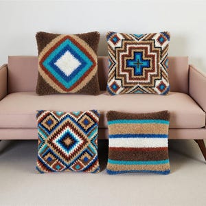 Könnte beinhalten: Vier dekorative Kissen mit geometrischen Mustern. Die Kissen weisen Designs in Braun-, Blau-, Weiß- und Beigetönen auf. Die Kissen liegen auf einem rosa Sofa.