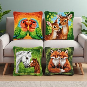 May include: Four decorative throw pillows with animal designs. The pillows feature images of two lovebirds, deer, a horse and foal, and two foxes. Each pillow has a textured, fringed border and is placed on a light-colored sofa.