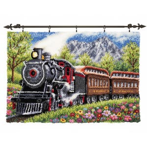 May include: A textile wall hanging shows a vintage steam train in a scenic landscape. The train is black and red, with brown carriages. The scene includes green trees, colourful flowers, and a mountain backdrop. The hanging is mounted on a dark metal rod.