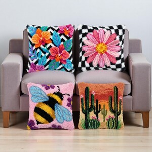 May include: Four decorative throw pillows with colorful designs. One pillow features a floral pattern with orange, pink, and blue flowers on a black and white zigzag background. Another has a pink daisy on a black and white checkerboard. The other two pillows have a bee and a desert scene.