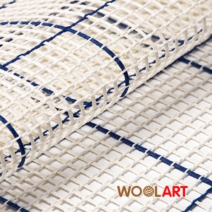Puede incluir: Lienzo blanco con un patr&oacute;n de cuadr&iacute;cula azul. El lienzo est&aacute; doblado, mostrando el lado posterior. El lienzo est&aacute; etiquetado con "WOOLART" en la esquina inferior derecha.