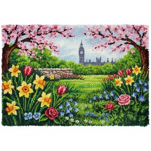 Könnte beinhalten: Ein farbenfroher Gobelin-Teppich, der eine Parkszene mit dem Big Ben im Hintergrund darstellt. Der Vordergrund zeigt gelbe Narzissen, rote Tulpen und rosa Kirschblüten. Eine Steinmauer und grünes Gras vervollständigen die Landschaft.