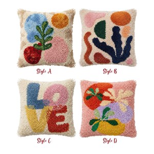 May include: Four square decorative throw pillows with abstract designs. Styles include colorful shapes, botanical motifs, and the word "LOVE". Each pillow has a textured, off-white background and a fringed border. The text "Style A", "Style B", "Style C", and "Style D" are below each pillow.
