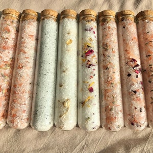 8 x 45ml clear glass test tubes with round bottom with cork stoppers. All 8 tubes are filled with different scent bath salts. Lavender, lavender eucalyptus, rose, eucalyptus peppermint, chamomile, lavender rosemary, oatmeal and vanilla, eucalyptus.