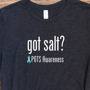 May include: A dark heather grey t-shirt with white text that reads "got salt?" and a teal ribbon with the text "POTS Awareness".