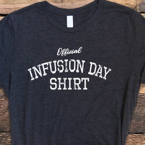 May include: A dark gray t-shirt with the text "Official Infusion Day Shirt" in white.
