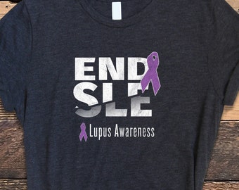 Może przedstawiać: Szara koszulka z nadrukiem "END SLE" w kolorze białym z fioletową wstążką. Pod tekstem znajduje się napis "Lupus Awareness".