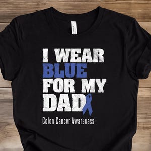 May include: Black t-shirt with the text "I Wear Blue For My Dad" in white and blue. A blue ribbon graphic is included, with the words "Colon Cancer Awareness" below the text.