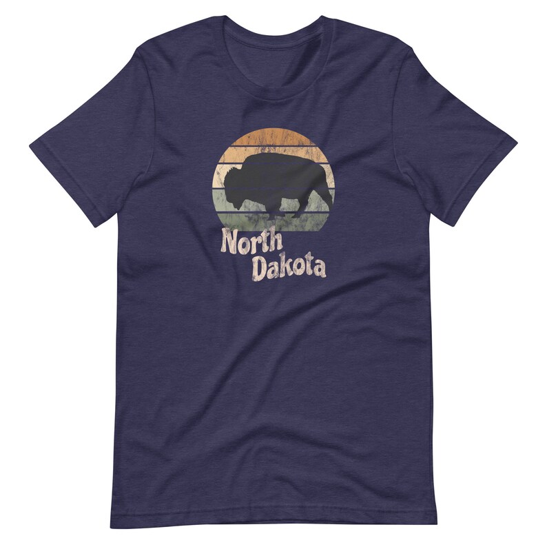May include: A navy blue t-shirt with a vintage-style graphic of a bison silhouette in front of a sunset with the text "North Dakota".