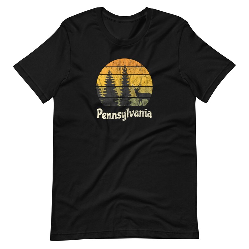 Op de afbeelding: Zwart T-shirt met een vintage-stijl grafische afbeelding van een zonsondergang met bomen en een hert voor de tekst "Pennsylvania".