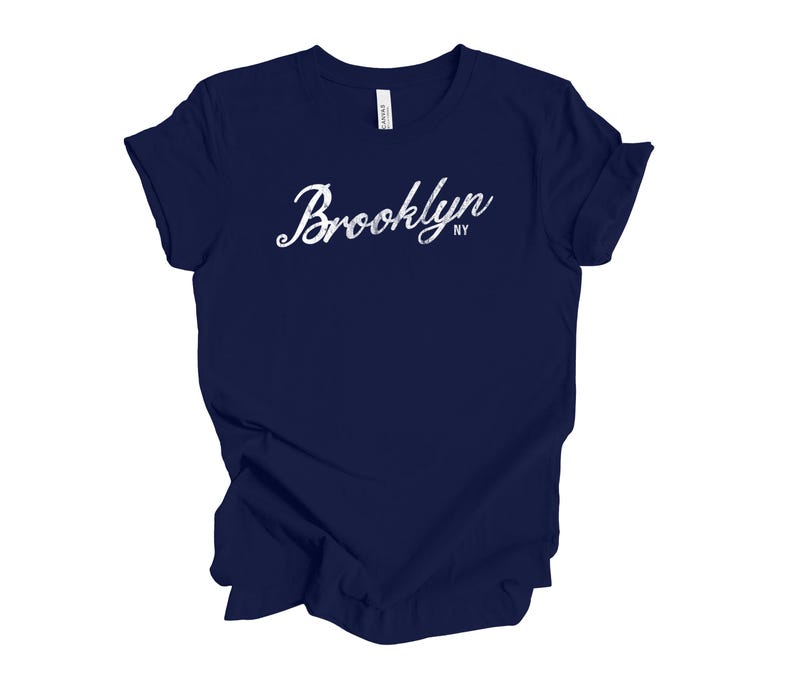 Op de afbeelding: Een marineblauw t-shirt met het woord "Brooklyn" in witte letters op de voorkant. De tekst "NY" staat onder het woord "Brooklyn". Het shirt is gemaakt van een zacht materiaal.