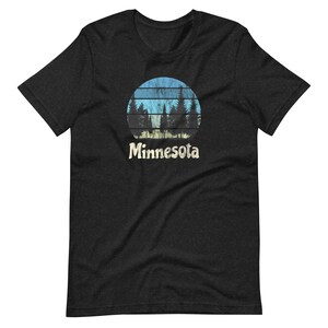 May include: Black t-shirt with a vintage-style graphic of a blue and yellow sunset with trees in front of it. The text "Minnesota" is below the graphic.