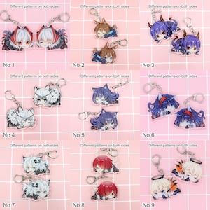 May include: A selection of nine anime-style keyrings. Each keyring showcases a unique character design with diverse hair colours and outfits. The keyrings are attached to silver-coloured metal rings. The text "Different patterns on both sides" is above each pair of keyrings.
