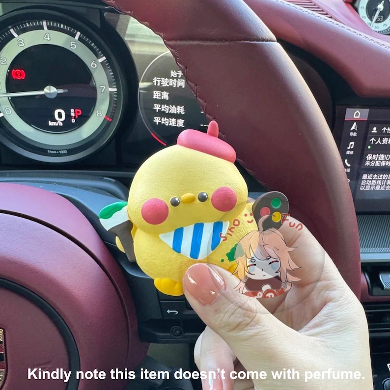 May include: A yellow chick figurine with a red beak and blue and white striped scarf. The chick is holding a small, colorful traffic light. The figurine is sitting in a car dashboard.
